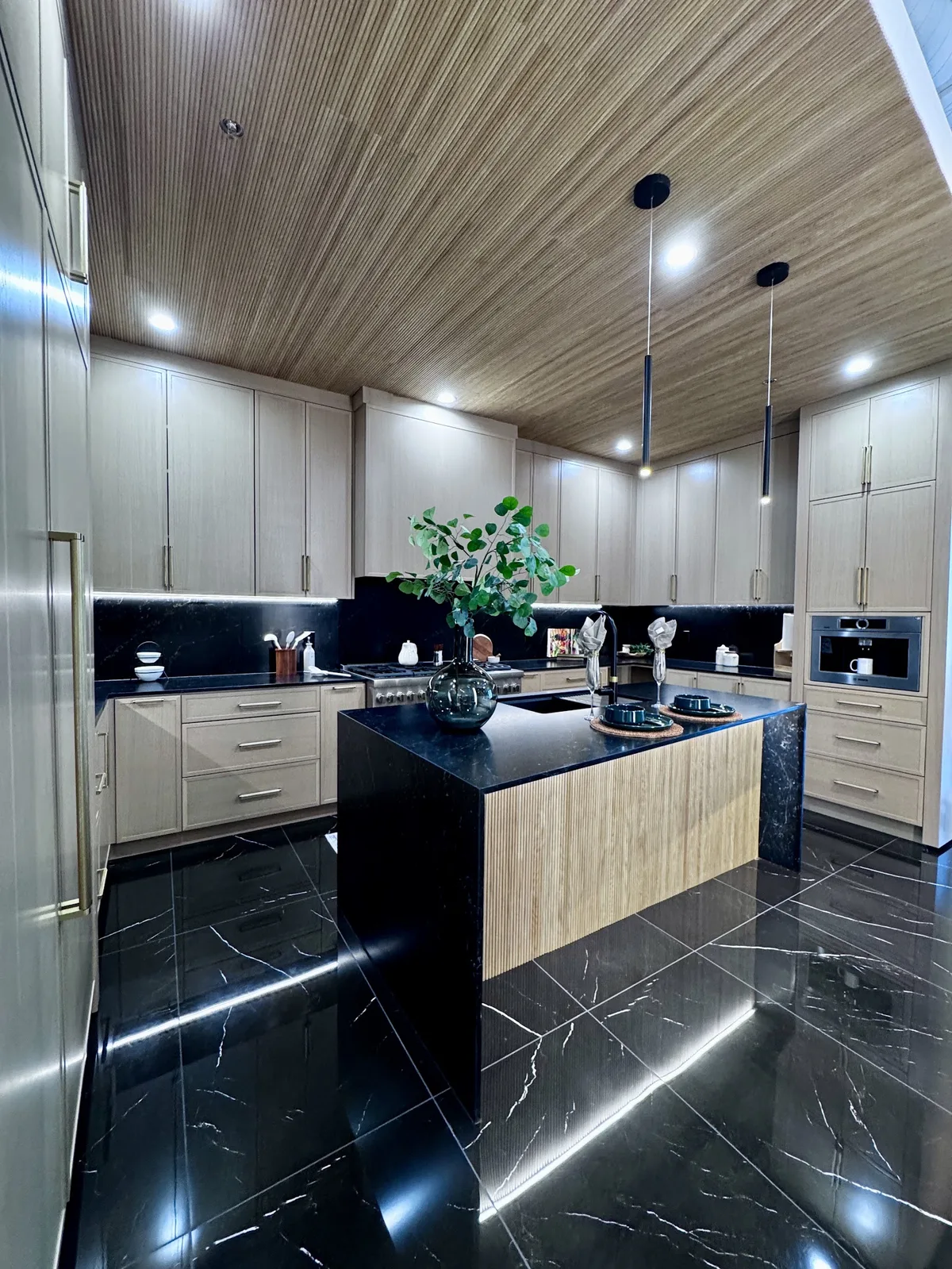 Kitchen display with a marble waterfall island and stone countertops at the Modern Concepts Design showroom